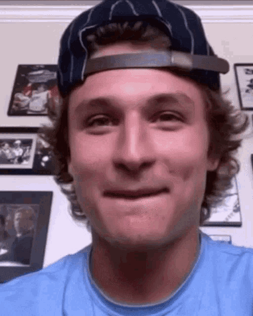 a man wearing a baseball cap and a blue shirt is smiling .
