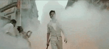 a man is standing in a smokey area holding a sword .