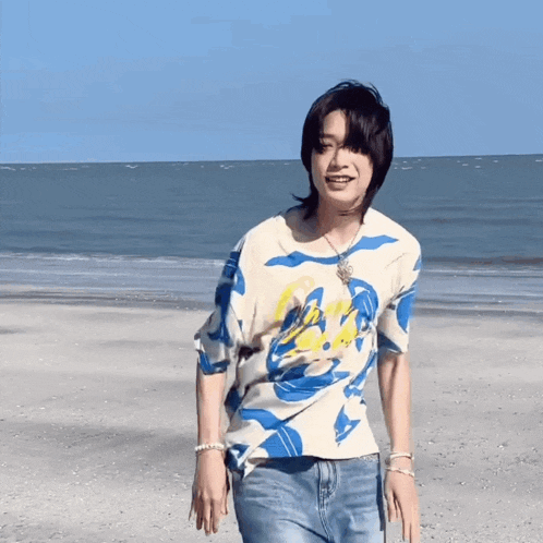 a man in a blue and white shirt is walking on a beach .