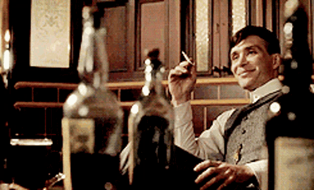 a man smoking a cigarette in front of a bottle
