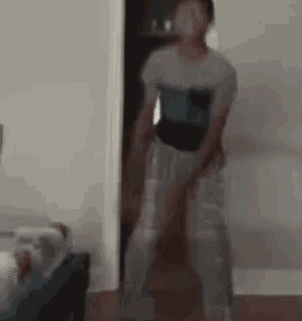 a blurry picture of a person standing in a room with their legs crossed .