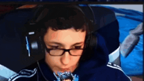 a young man wearing glasses and headphones is eating a piece of food