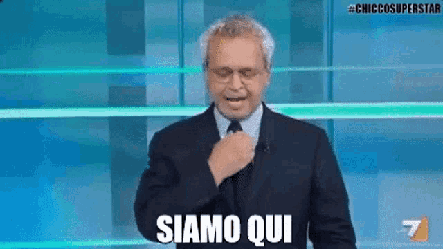 a man in a suit and tie is standing in front of a microphone and says siamo qui .