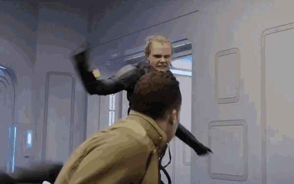 a woman in a black suit is fighting a man