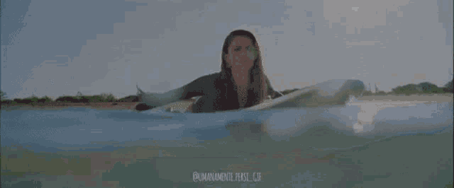 a woman is swimming in the ocean with a blurry background