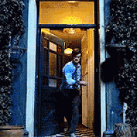a man in a blue shirt and tie is walking through a door .