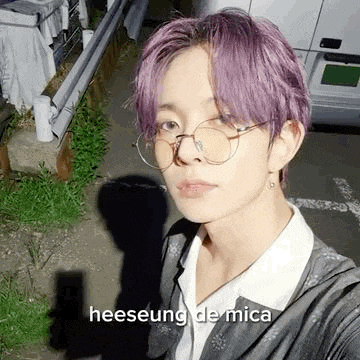 a person with purple hair and glasses is taking a selfie .