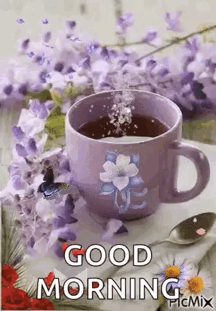 a cup of coffee with purple flowers and a spoon on a table .