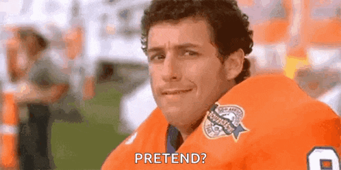 a man in an orange football jersey is sitting on a field and talking to the camera .