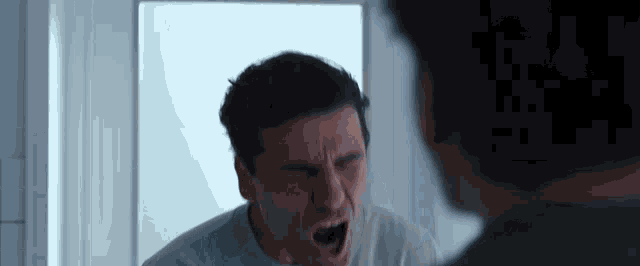 a man is looking at himself in a mirror and screaming