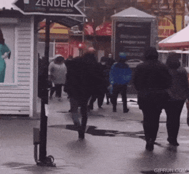 a group of people walking down a street in front of a sign that says zenden