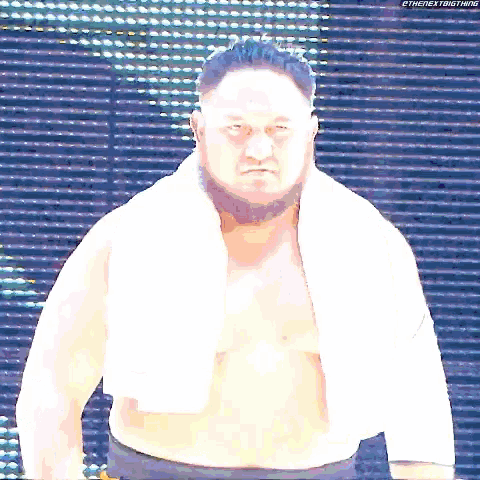 a shirtless man with a towel around his neck stands in front of a screen that says thenextbigthing