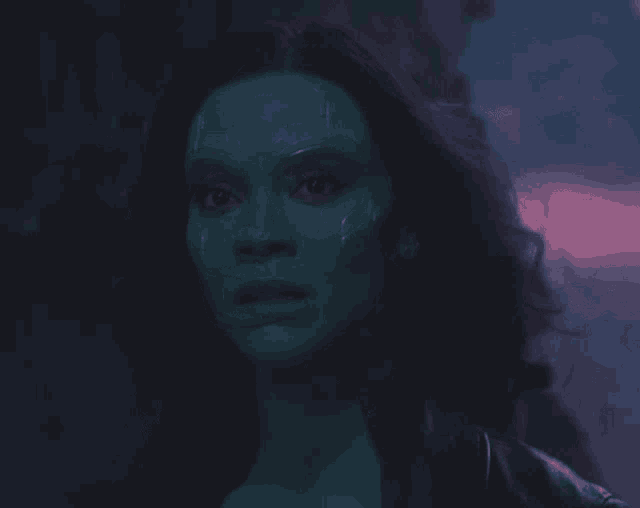 a close up of a woman 's face with green paint on her face