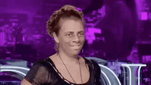 a woman is standing in front of a purple background and making a funny face .