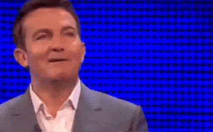 a man in a suit and white shirt is making a funny face in front of a blue background .