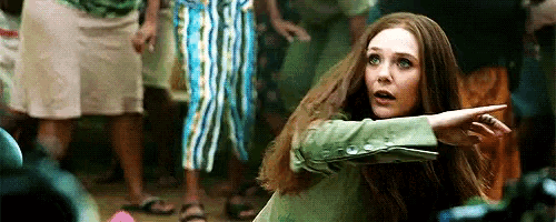 a woman with long hair is standing in front of a crowd of people and pointing at something .