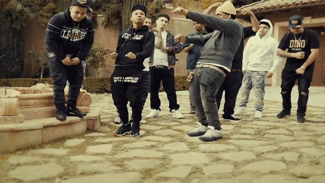 a group of men are standing in front of a fountain and one of them is wearing a shirt that says dino