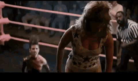 a woman is standing in a boxing ring with a referee in the background