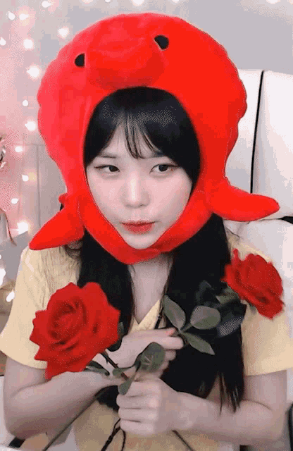 a girl wearing a red octopus hat is holding two red roses