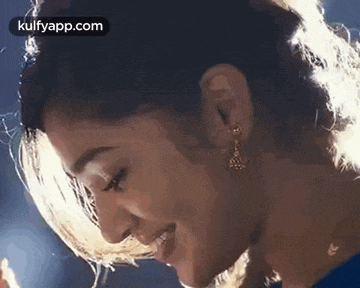 a close up of a woman 's face smiling with her hair blowing in the wind .