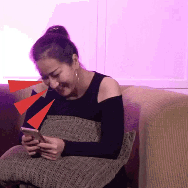 a woman sits on a couch looking at her cell phone