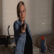 a woman in a denim jacket is pointing a gun