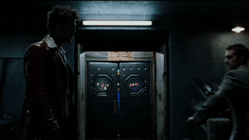 two men standing next to each other in front of a door that says ' elevator ' on it
