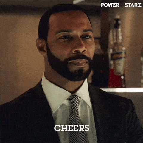 a man with a beard is wearing a suit and tie and says cheers .