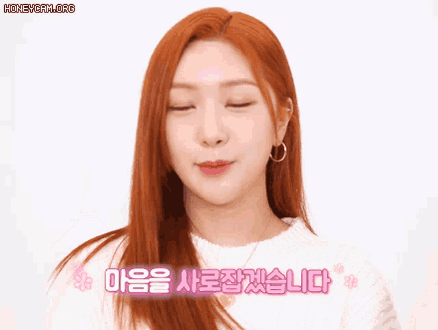 a woman with red hair is wearing a white sweater and smiling with the words honeycam.org above her
