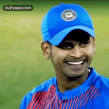 a man wearing a blue hat and a red and blue shirt is smiling .