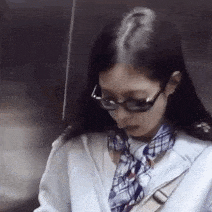 a woman wearing sunglasses and a scarf is looking down .