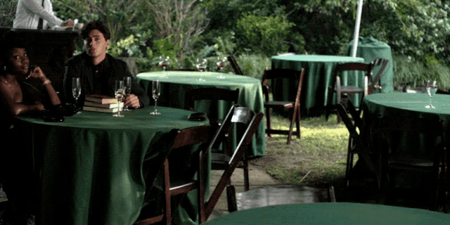 a man and woman sit at a table with green tables and chairs
