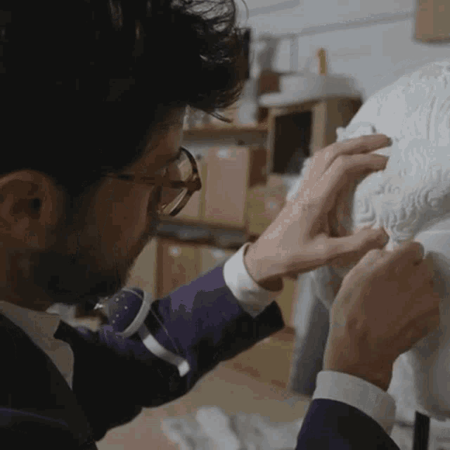 a man wearing glasses and a purple shirt is working on a statue