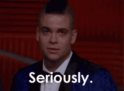 a man with a mohawk is wearing a tuxedo and bow tie and is looking at the camera .