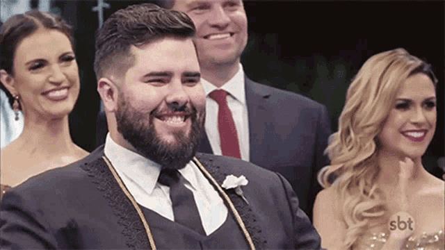 a man in a suit and tie is smiling while standing next to a woman in a dress .
