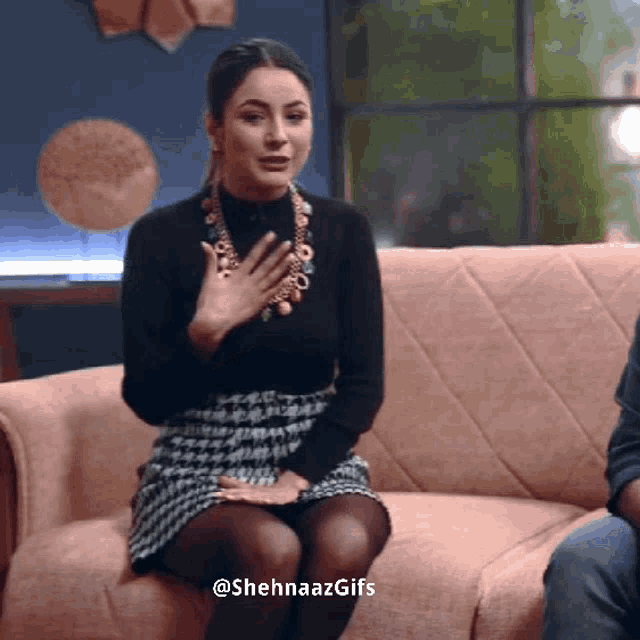 a woman sitting on a couch with the hashtag shehnaazgifs on the bottom