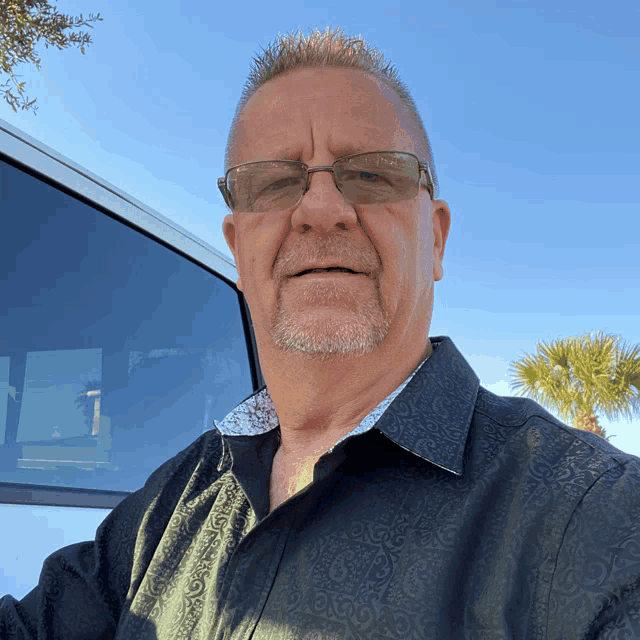 a man wearing sunglasses and a black shirt is standing in front of a white van