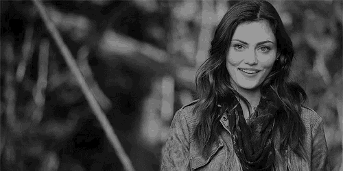 a black and white photo of a woman in a jacket and scarf smiling .