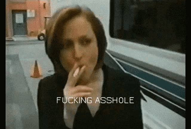 a woman is smoking a cigarette and the words fucking asshole are on the screen