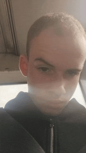 a young man is taking a selfie with his face visible while sitting in a car .