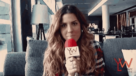 a woman sitting on a couch holding a microphone with xw on it
