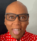 a man wearing glasses and a red polka dot shirt is sticking out his tongue .