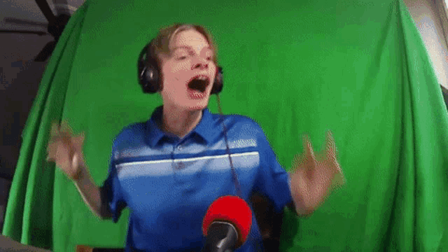 a boy wearing headphones and a blue shirt is singing into a microphone .