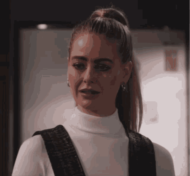 a woman in a white turtleneck and black overalls