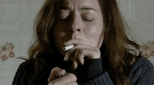 a woman is crying while smoking a cigarette with her eyes closed