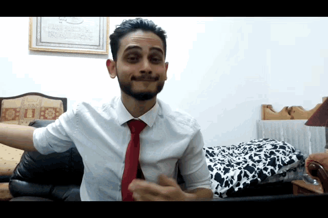 a man in a white shirt and red tie is making a face