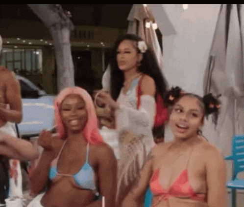 a group of women in bikinis are standing next to each other and laughing .
