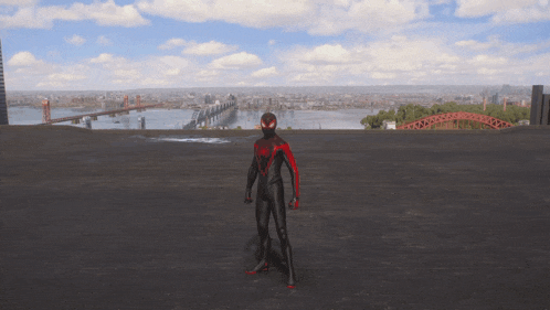 a man in a red and black spiderman suit stands on a rooftop overlooking a city