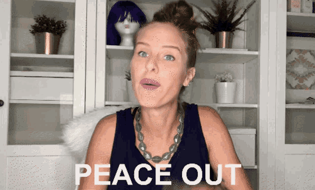 a woman says peace out in front of a shelf