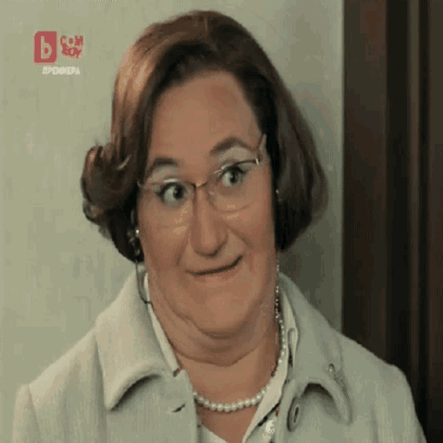 a woman wearing glasses and a pearl necklace is making a funny face in front of a sign that says bbox